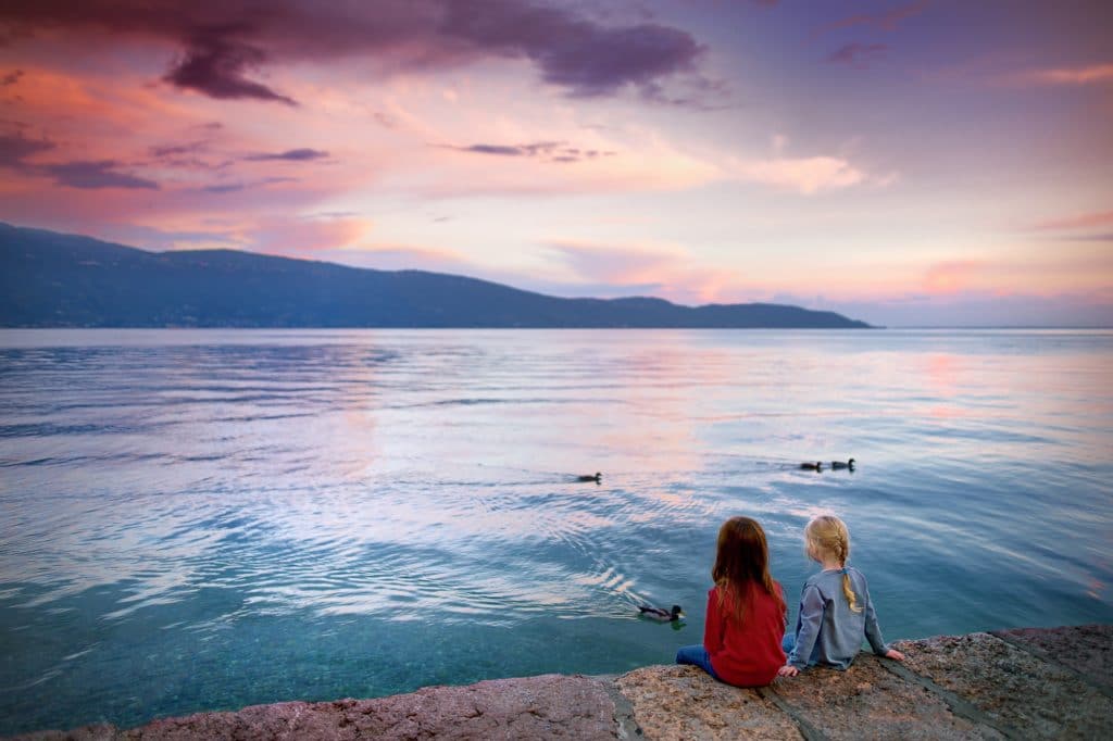 Two little girls enjoying beautiful sunset in Gargnano, a small town and comune in the province of Brescia, in Lombardy. It is situated on the western shore of Lake Garda.